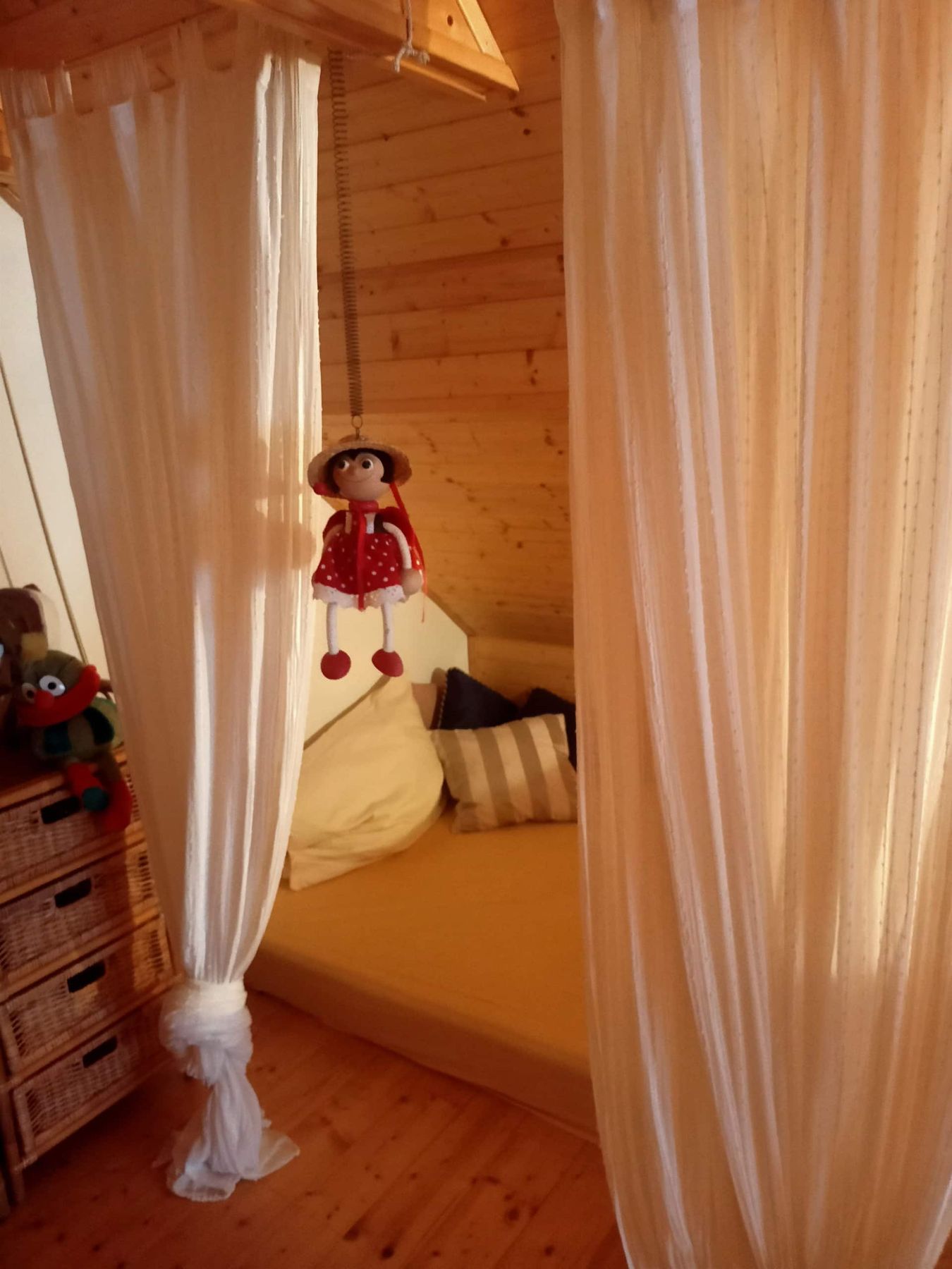 Hrací koutek za světlými závěsy pod střechou
